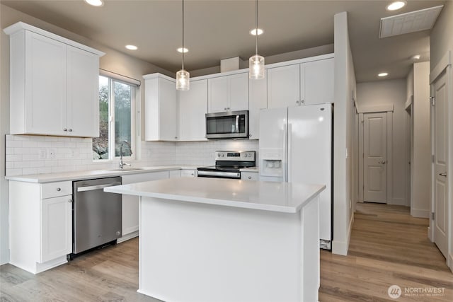 kitchen featuring stainless steel appliances, light countertops, white cabinetry, and a center island