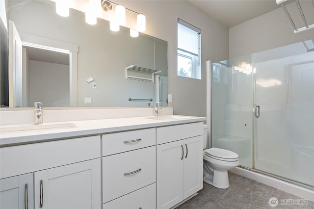 full bath with double vanity, a sink, toilet, and a shower stall