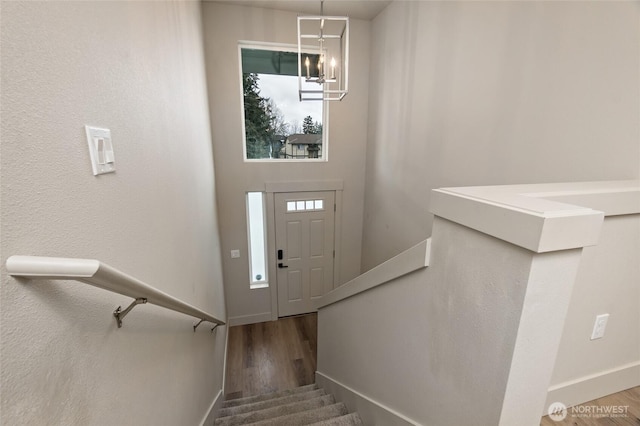 foyer featuring a chandelier, stairway, wood finished floors, and baseboards