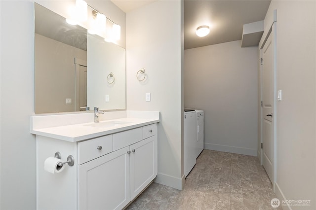 bathroom featuring baseboards, vanity, and washer and dryer