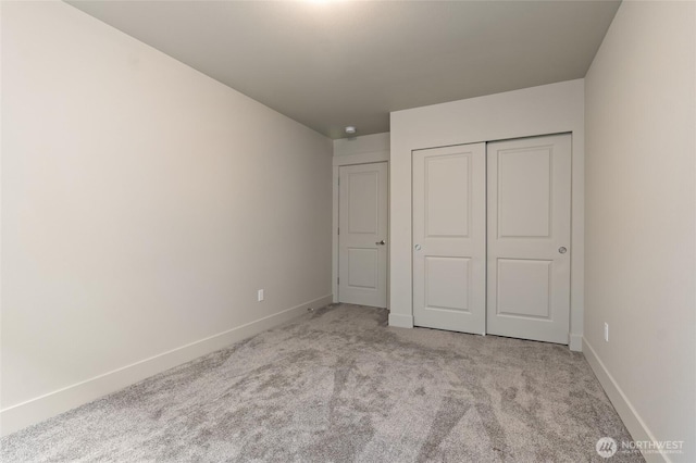 unfurnished bedroom with baseboards, a closet, and light colored carpet