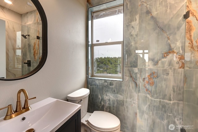 bathroom with vanity, tiled shower, and toilet