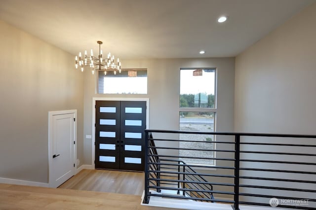 entryway with light hardwood / wood-style floors, an inviting chandelier, and french doors