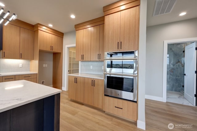 kitchen with double oven, light hardwood / wood-style floors, and light brown cabinets