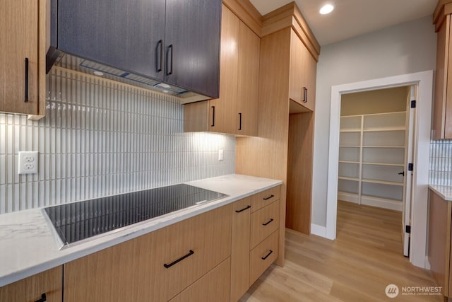 kitchen with black electric cooktop, tasteful backsplash, light hardwood / wood-style flooring, and light brown cabinets