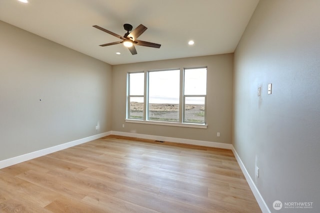 empty room with ceiling fan and light hardwood / wood-style flooring