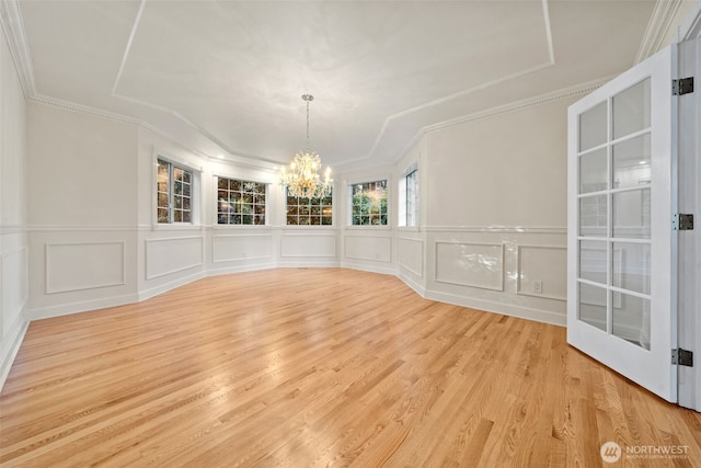 unfurnished dining area featuring a chandelier, crown molding, and light hardwood / wood-style flooring