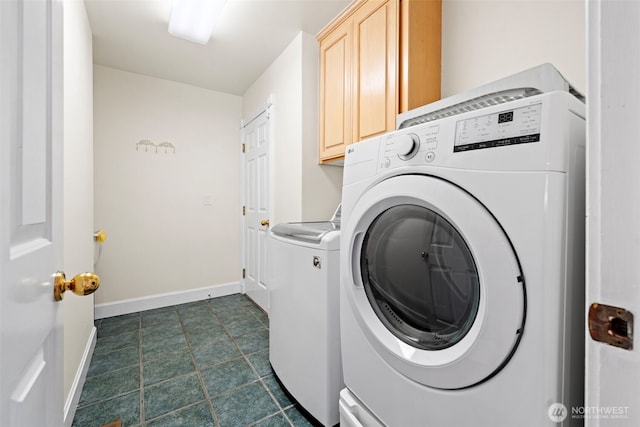 clothes washing area with washer and clothes dryer and cabinets