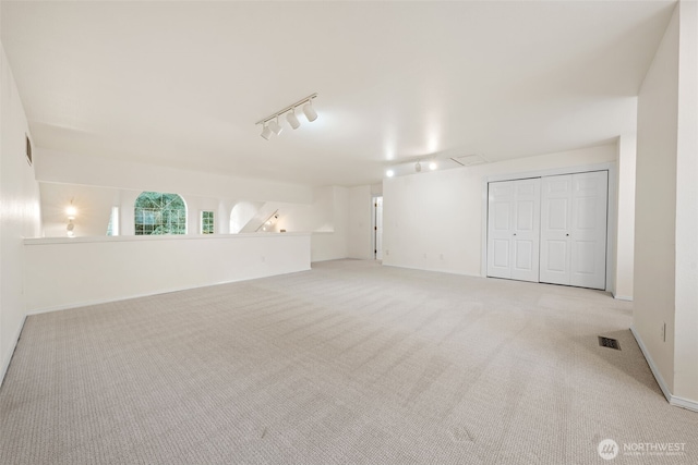 unfurnished room featuring rail lighting and light colored carpet