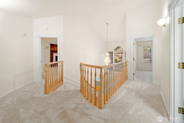 hallway with vaulted ceiling and light carpet