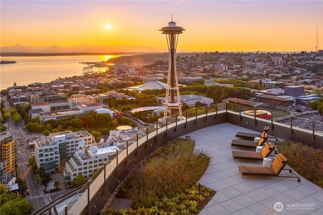 aerial view at dusk featuring a water view and a view of city