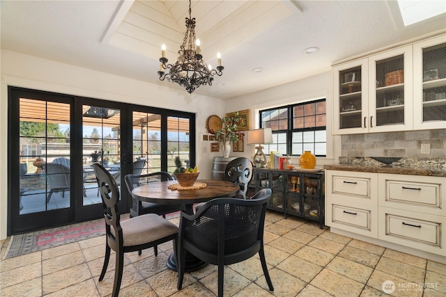 dining room with plenty of natural light, a tray ceiling, a notable chandelier, and french doors