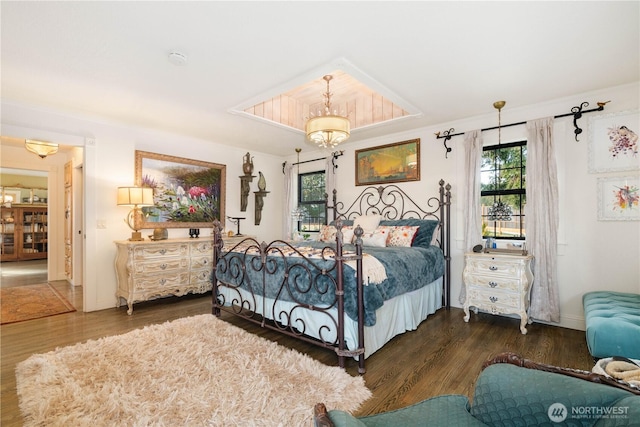 bedroom with baseboards, a chandelier, and dark wood-type flooring