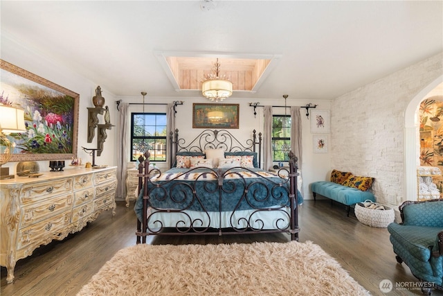 bedroom featuring dark wood-style floors, arched walkways, and multiple windows