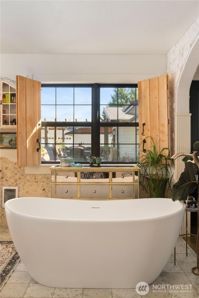 bathroom featuring marble finish floor, visible vents, and a freestanding bath