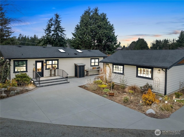 ranch-style house with concrete driveway and a shingled roof