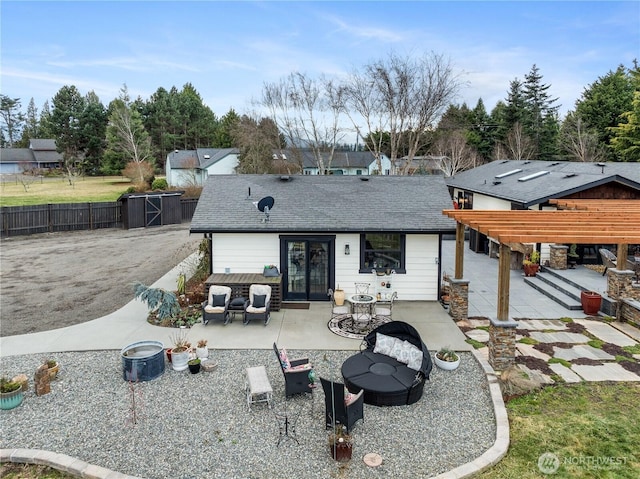 back of property featuring a shingled roof, a patio, a fire pit, and fence