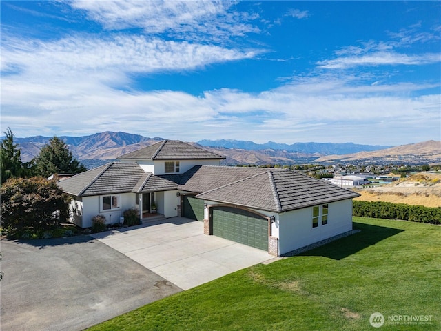 view of front of house featuring a front lawn, a mountain view, and an attached garage