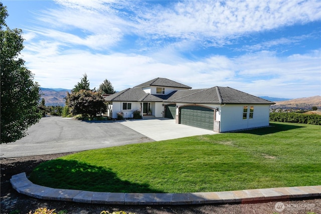 view of front of property with a tile roof, concrete driveway, an attached garage, a mountain view, and a front lawn