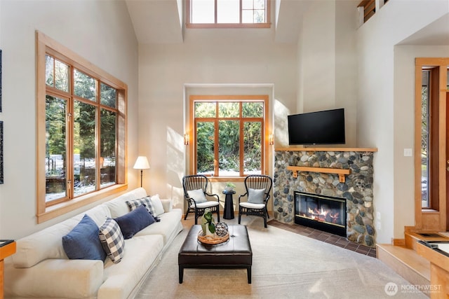 living room featuring a high ceiling and a stone fireplace