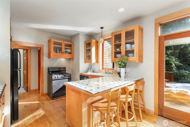 kitchen featuring sink, pendant lighting, a kitchen breakfast bar, black appliances, and kitchen peninsula