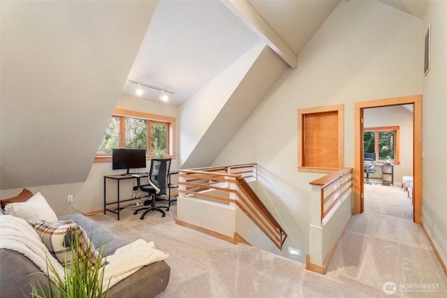 carpeted office space featuring lofted ceiling and track lighting