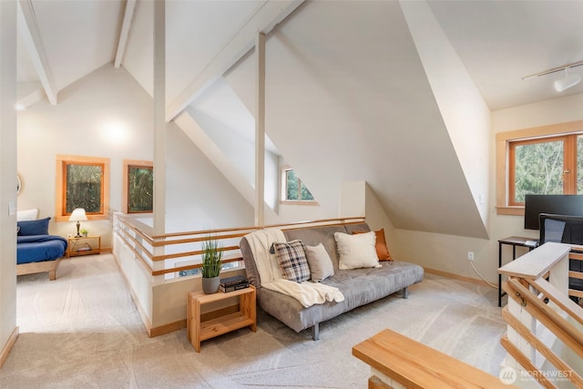 living room with track lighting, lofted ceiling with beams, and light colored carpet