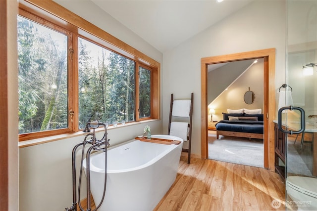 bathroom with hardwood / wood-style floors, a tub, and lofted ceiling