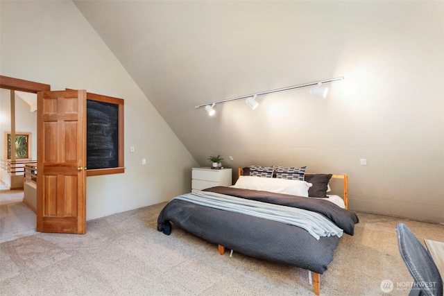 carpeted bedroom with vaulted ceiling and rail lighting