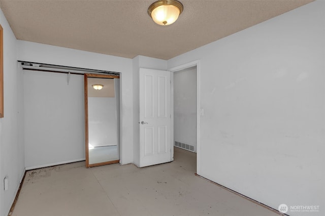 unfurnished bedroom featuring finished concrete flooring, a closet, visible vents, and a textured ceiling