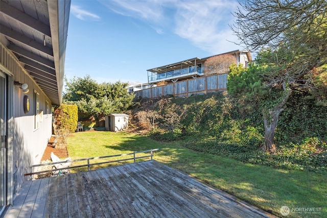 wooden deck featuring a storage shed, a lawn, and an outdoor structure