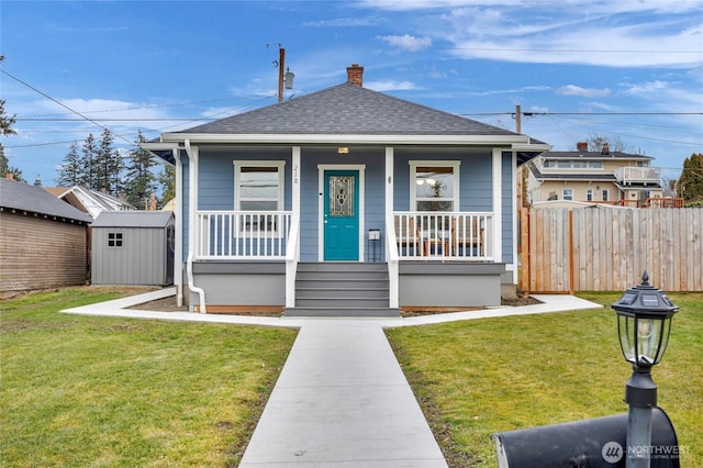 bungalow with a storage unit, covered porch, and a front yard