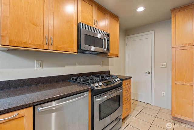 kitchen with dark stone counters, appliances with stainless steel finishes, light tile patterned flooring, and recessed lighting