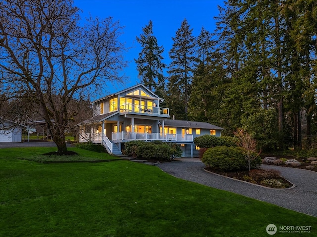 view of front of house featuring covered porch, a balcony, and a front lawn