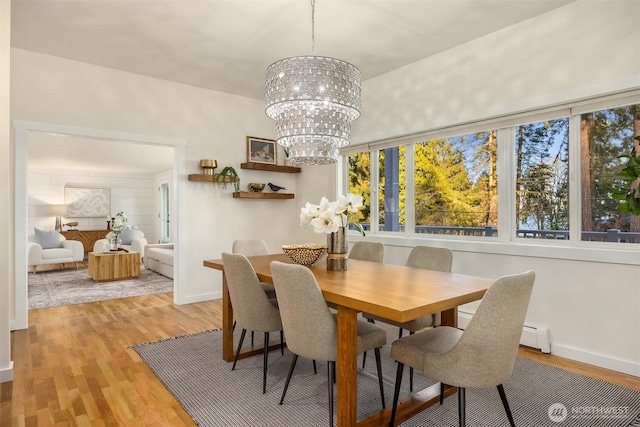 dining space featuring light wood-type flooring, baseboard heating, and a notable chandelier