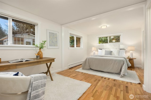 bedroom with wood-type flooring and a baseboard heating unit