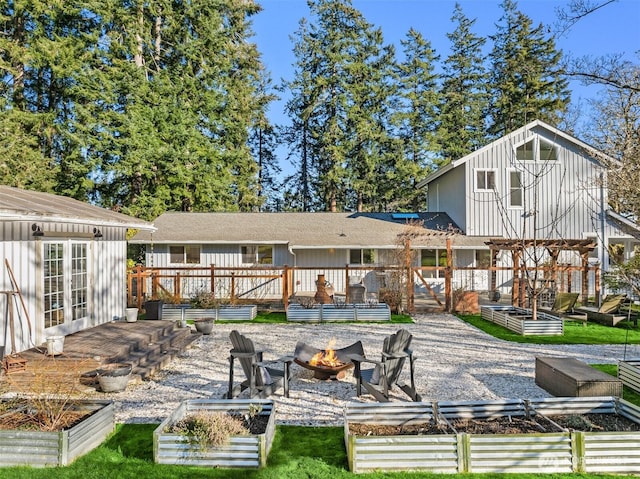 rear view of house with an outbuilding, a wooden deck, and an outdoor fire pit