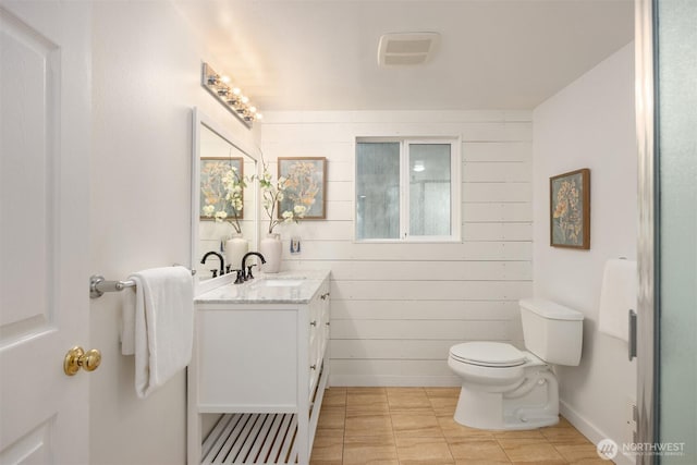 bathroom with toilet, vanity, and wooden walls