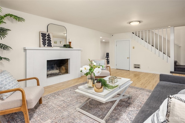 living room with a tiled fireplace and light hardwood / wood-style flooring