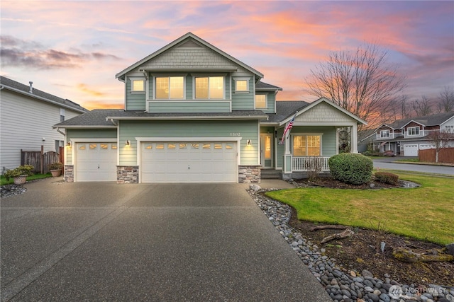 craftsman inspired home featuring a porch, stone siding, a yard, and concrete driveway