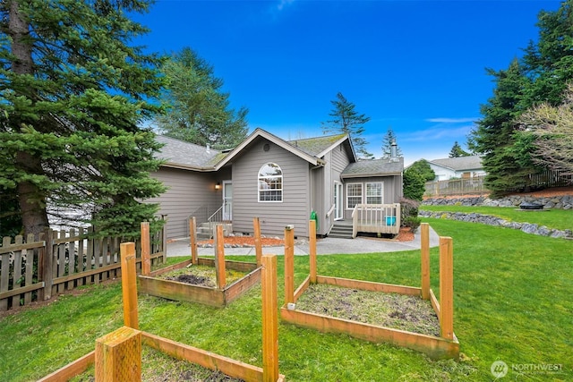 rear view of property featuring a garden, a yard, a wooden deck, and fence