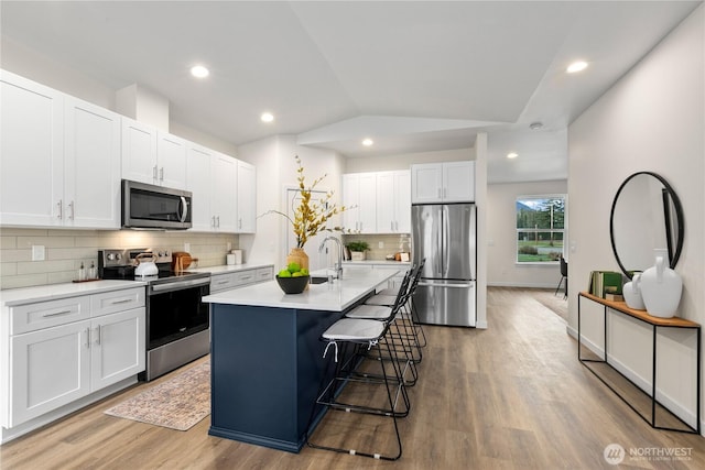 kitchen featuring lofted ceiling, light wood finished floors, light countertops, and appliances with stainless steel finishes