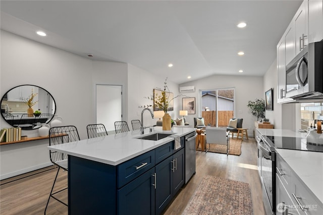 kitchen featuring a sink, light wood-type flooring, a kitchen breakfast bar, and appliances with stainless steel finishes