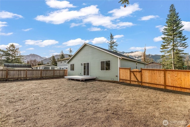 rear view of property featuring a deck with mountain view and a fenced backyard