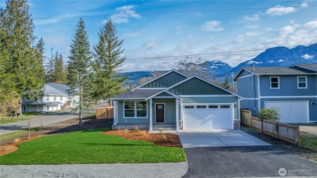 view of front of property with a front yard, fence, driveway, board and batten siding, and a mountain view