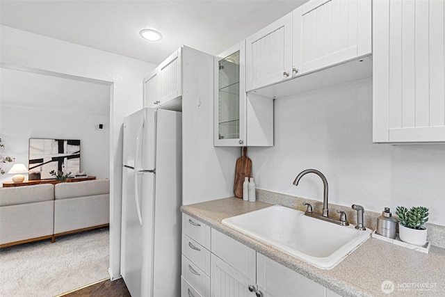 kitchen with sink, white cabinetry, dark colored carpet, and white refrigerator