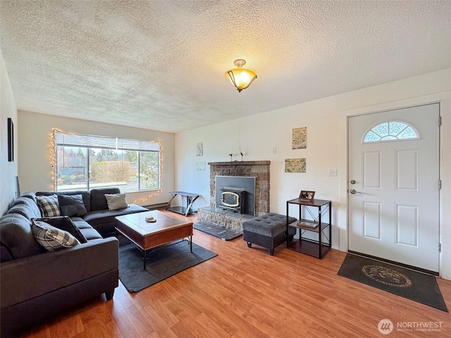 living room with a wood stove, a textured ceiling, and hardwood / wood-style floors