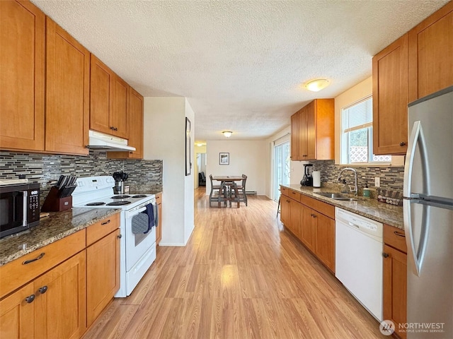 kitchen featuring white appliances, sink, light wood-type flooring, dark stone counters, and tasteful backsplash