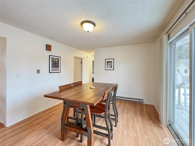 dining space featuring a baseboard heating unit, a textured ceiling, and light hardwood / wood-style floors