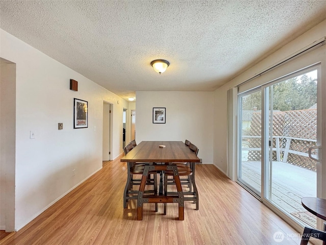 dining room with light wood-type flooring and a textured ceiling